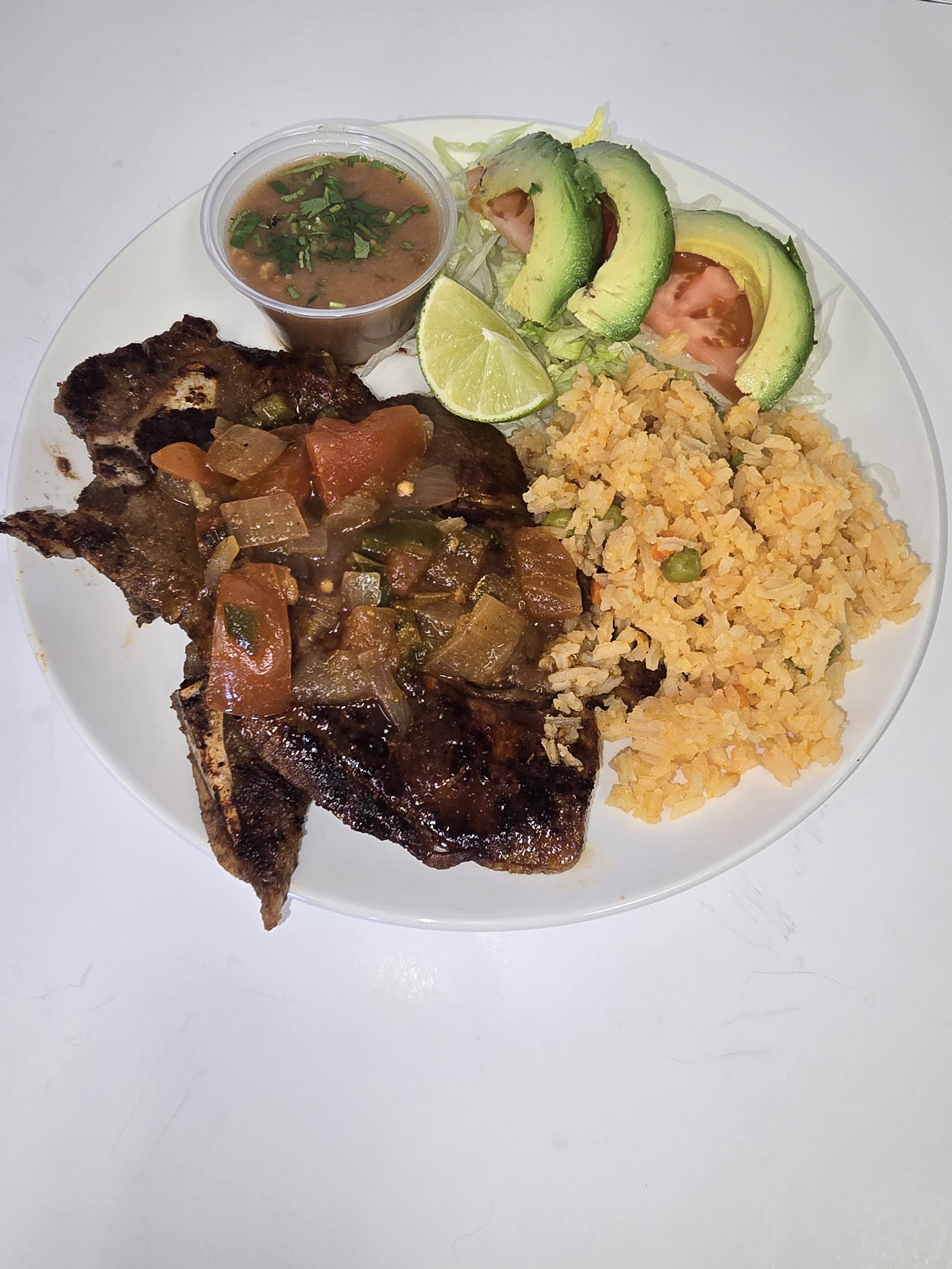 Grilled pork chop plate with rice, avocado, tomato and salsa