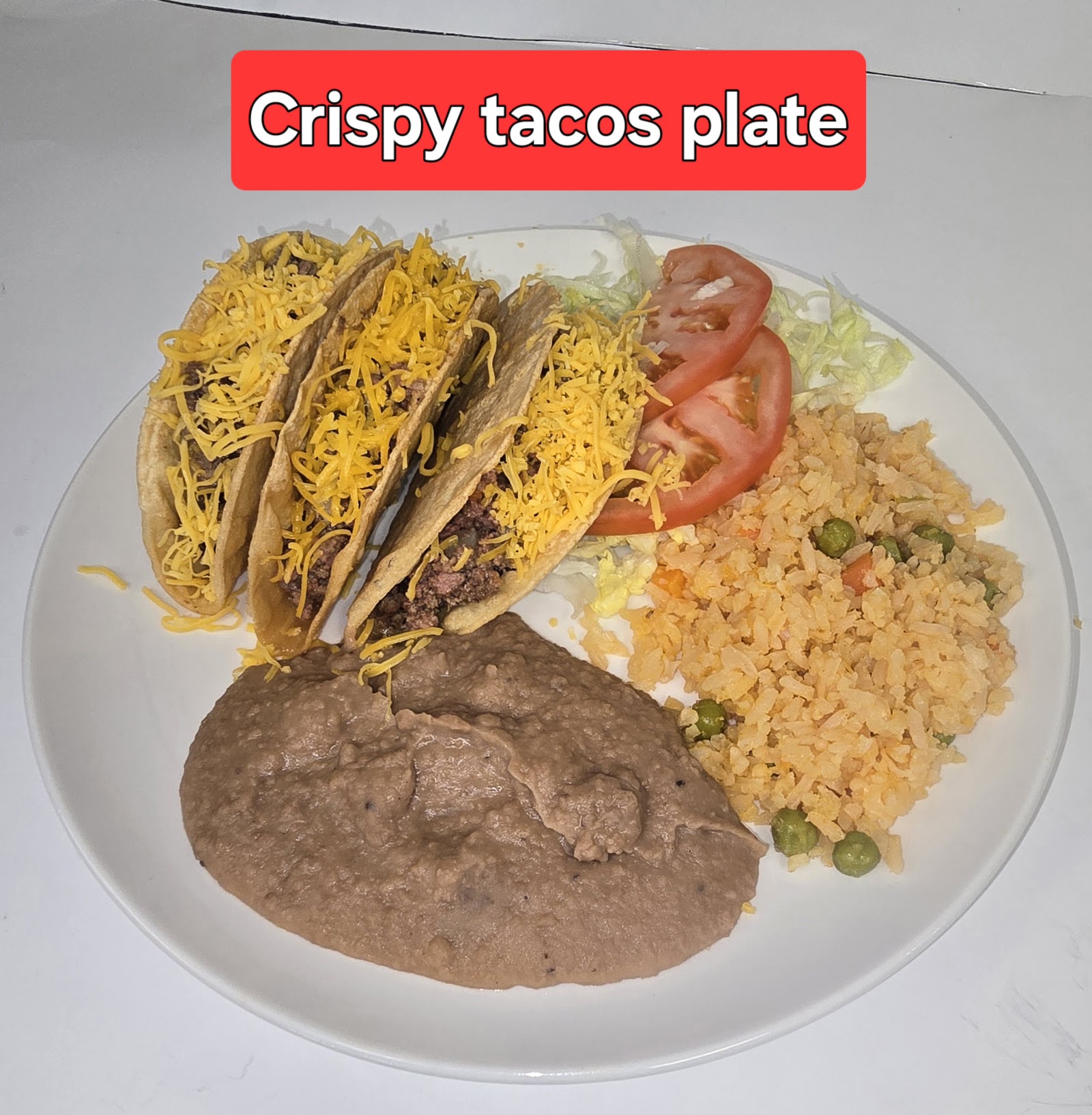Crispy beef tacos plate with rice, refried beans, lettuce and tomato
