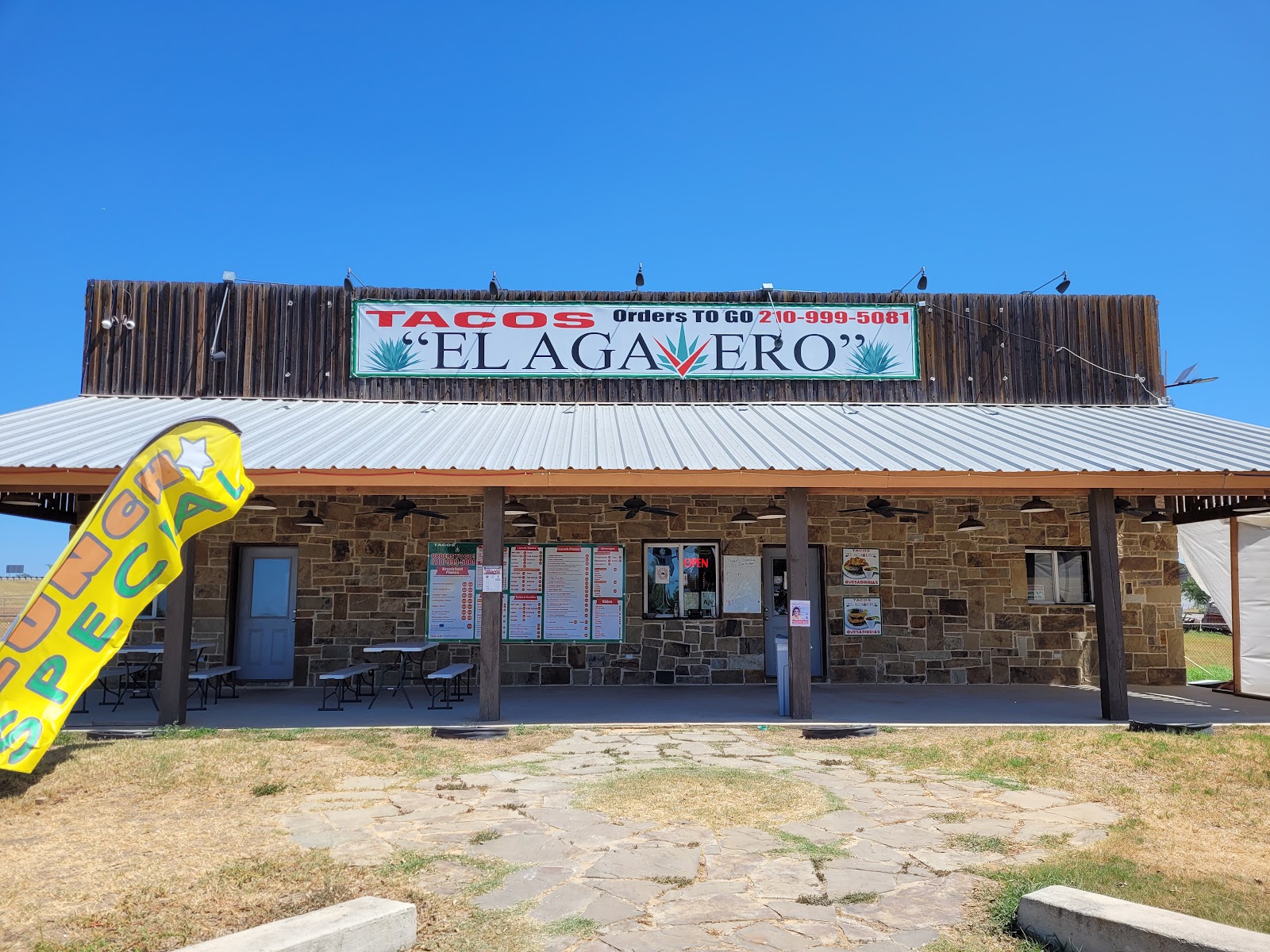Tacos El Agavero storefront with stone exterior, covered patio and menu boards